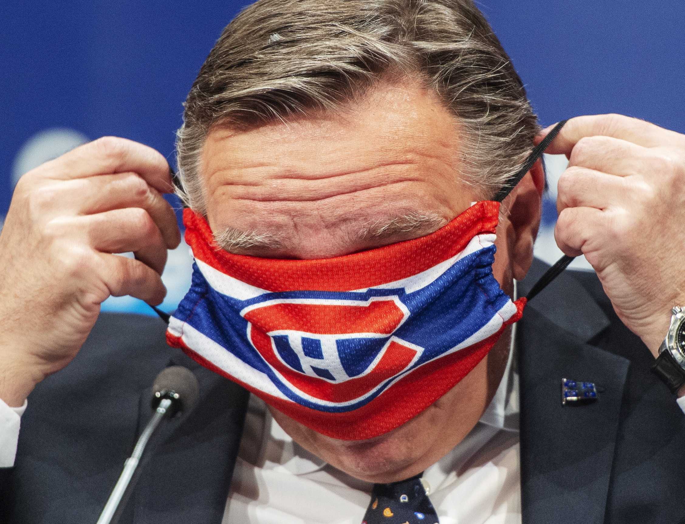 Photo of Legault putting on a Habs mask but seeming to have difficulty as the mask is covering his eyes.